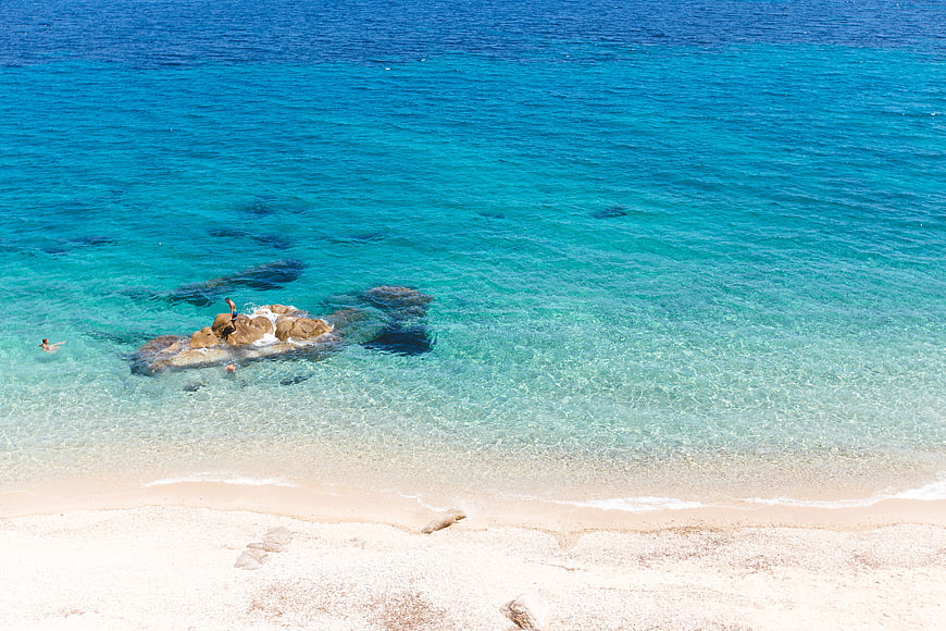 Aerial View of Turquoise Beach with Swimmers and Rocks
