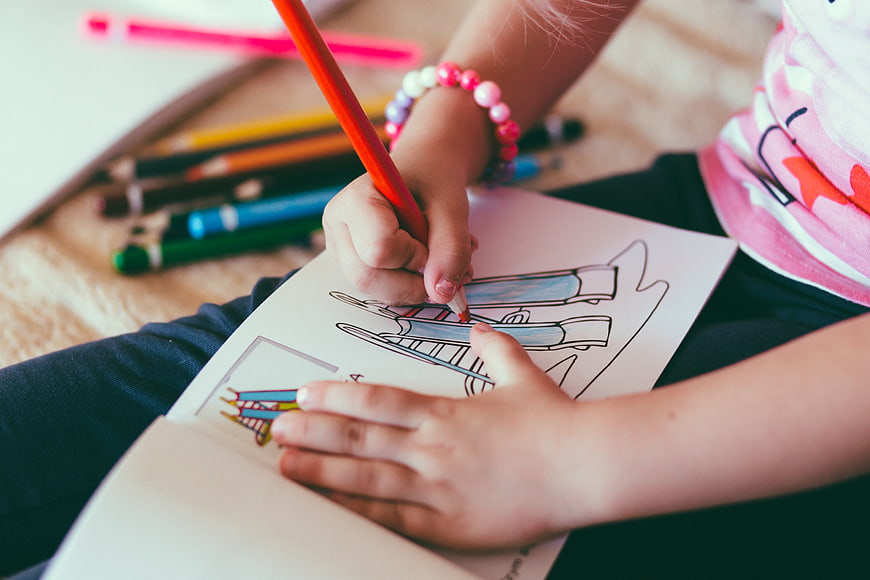 Child coloring with pencils in a drawing book