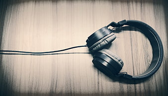 Black wired headphones on wooden background with copyspace