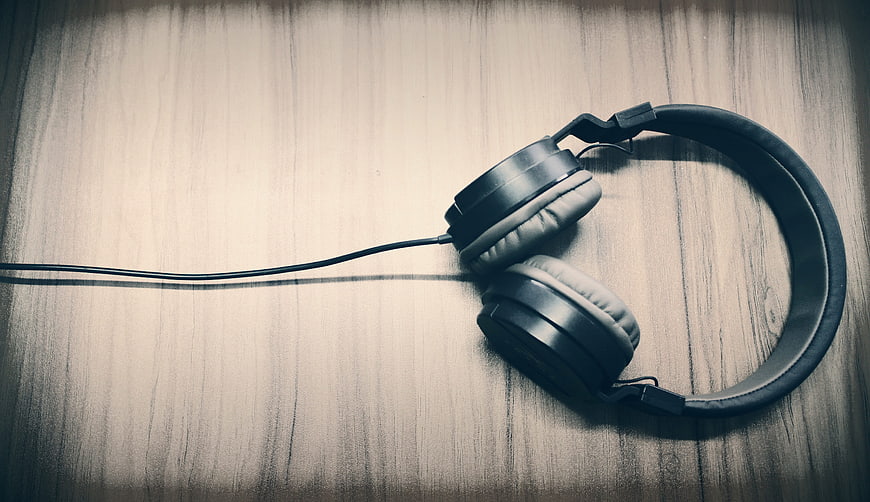 Black wired headphones on wooden background with copyspace