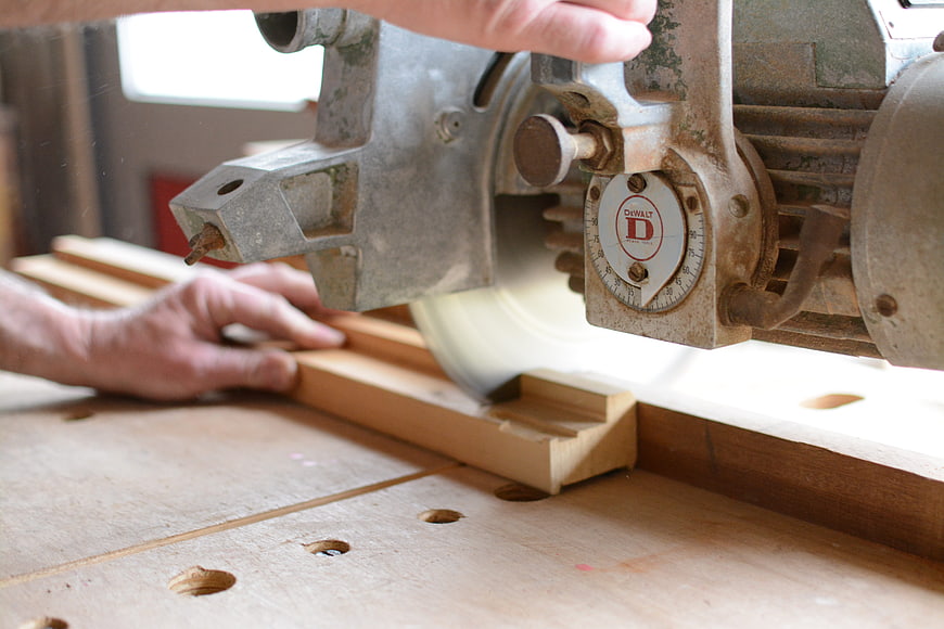 Carpenter using vintage DeWalt table saw to cut wood