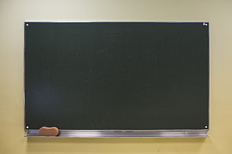 Empty black chalkboard with eraser on yellow wall