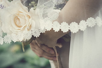 Close-up of bride holding bouquet with lace veil