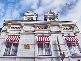Low angle view of white hotel facade with red striped awnings