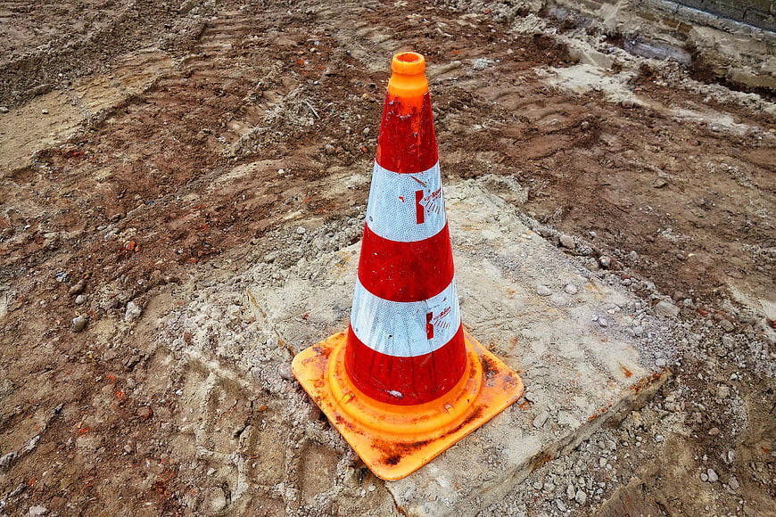 Worn red and white traffic cone on a dirt construction site