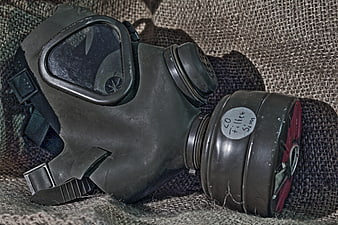 Vintage military gas mask with filter cartridge on burlap fabric