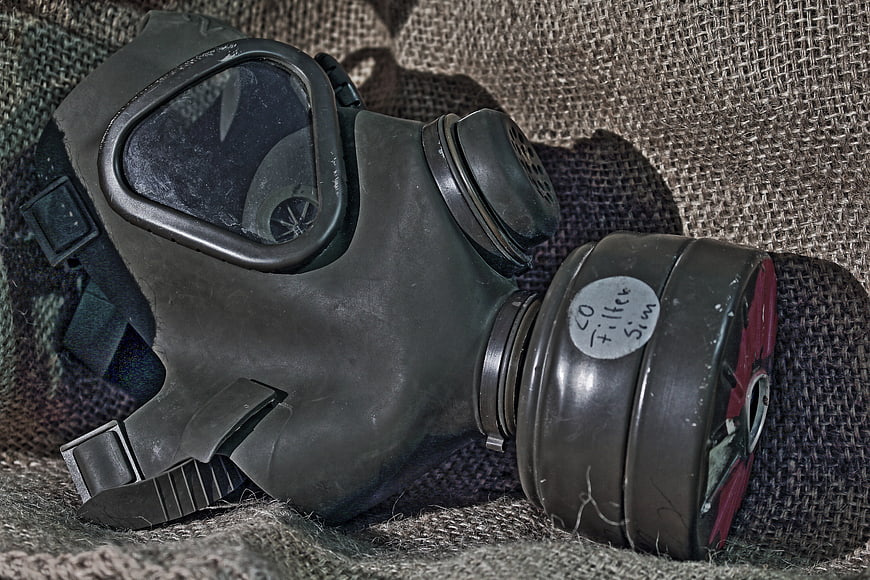 Vintage military gas mask with filter cartridge on burlap fabric