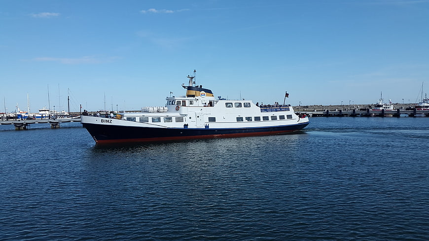 White and blue ferry boat named Binz sailing in harbor