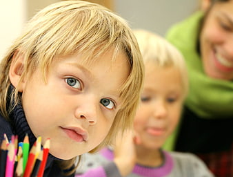 Close-up of young boy with colored pencils looking at camera