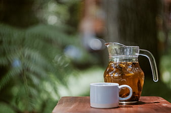 Glass Pitcher of Herbal Tea and White Mug on Wooden Table