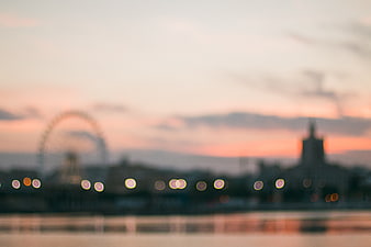 Blurred cityscape with bokeh lights and ferris wheel at sunset