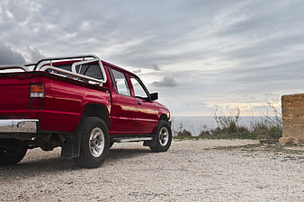 Red Pickup Truck Parked on Gravel Road Near Ocean
