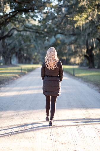 Woman Walking Away on Sunlit Path in Park