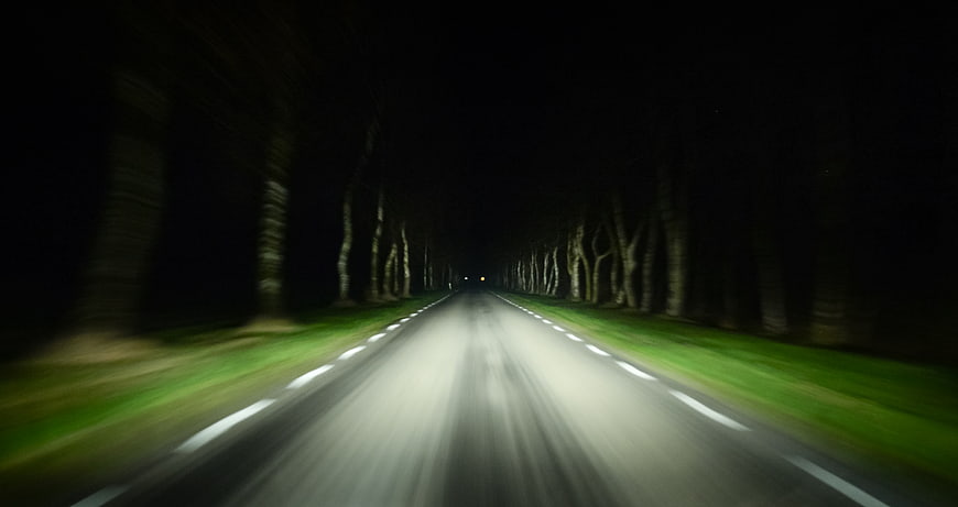 Motion blur night drive on tree-lined road