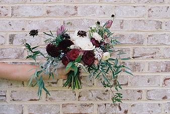 Rustic Wedding Bouquet With Dark Red And White Flowers Against Brick Wall
