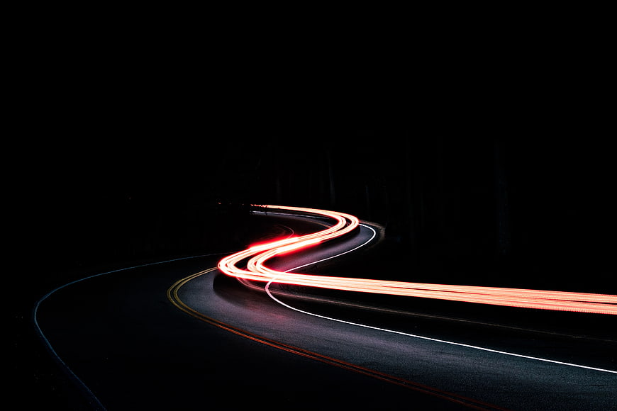 Red light trails on a winding road at night
