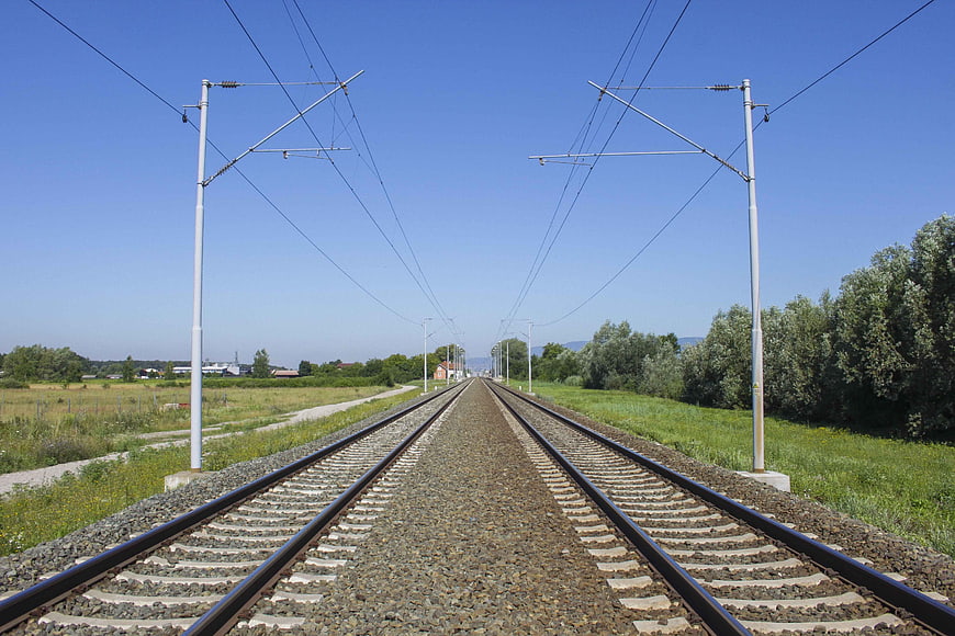 Double railway tracks stretching into the distance under a clear blue sky