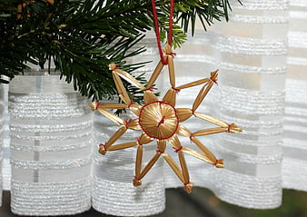 Traditional straw star Christmas ornament on pine branch