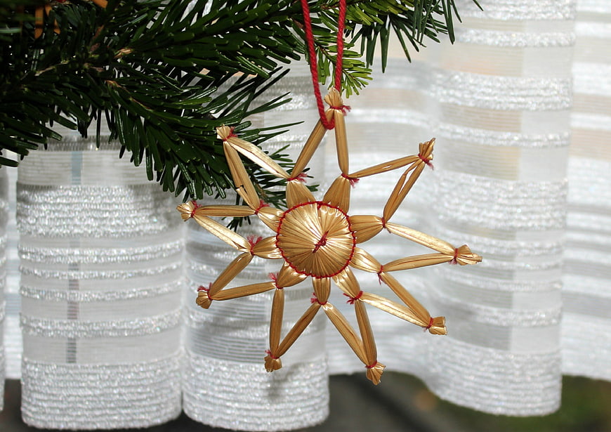 Traditional straw star Christmas ornament on pine branch