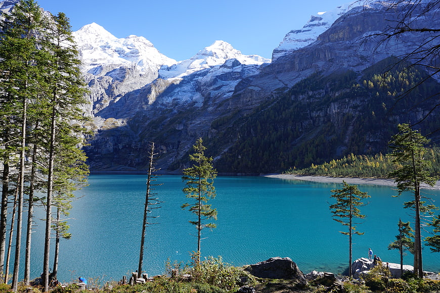 Turquoise alpine lake surrounded by snow-capped mountains and pine trees