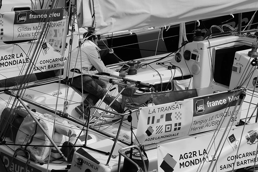 Sailor steering racing yacht in black and white