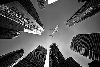 Black and white airplane flying over skyscrapers