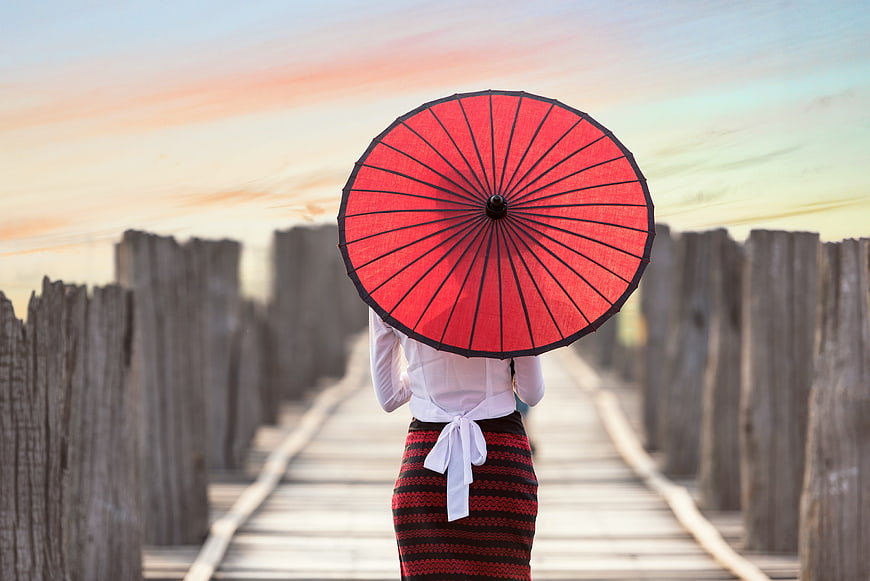 Woman with Red Parasol Walking on Wooden Bridge