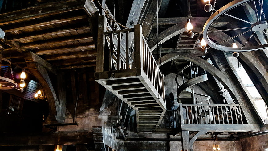 Dark rustic wooden staircase interior with spiral stairs and beams