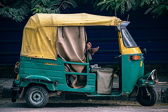 Green and yellow auto rickshaw parked on street