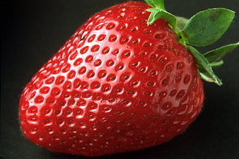 Close-up of a ripe red strawberry on black background