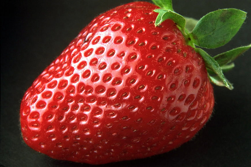Close-up of a ripe red strawberry on black background