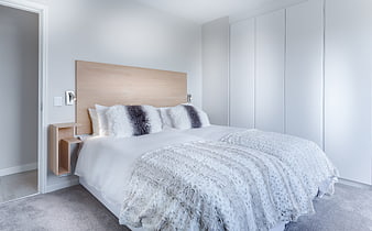Modern Minimalist Bedroom Interior With White Bedding And Wood Headboard