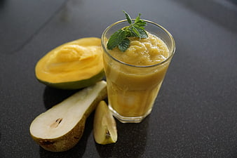 Mango and pear smoothie in a glass with fresh fruit garnish