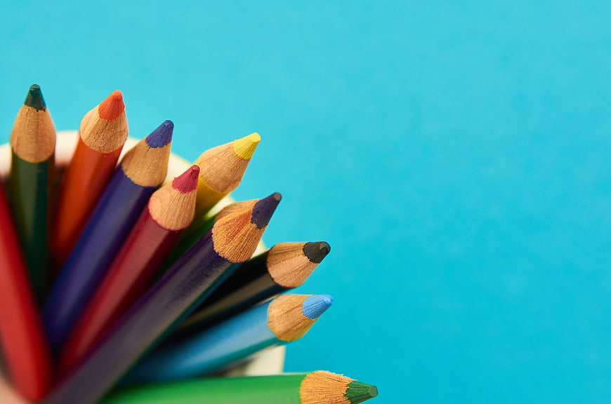 Colorful Pencils in Cup on Blue Background