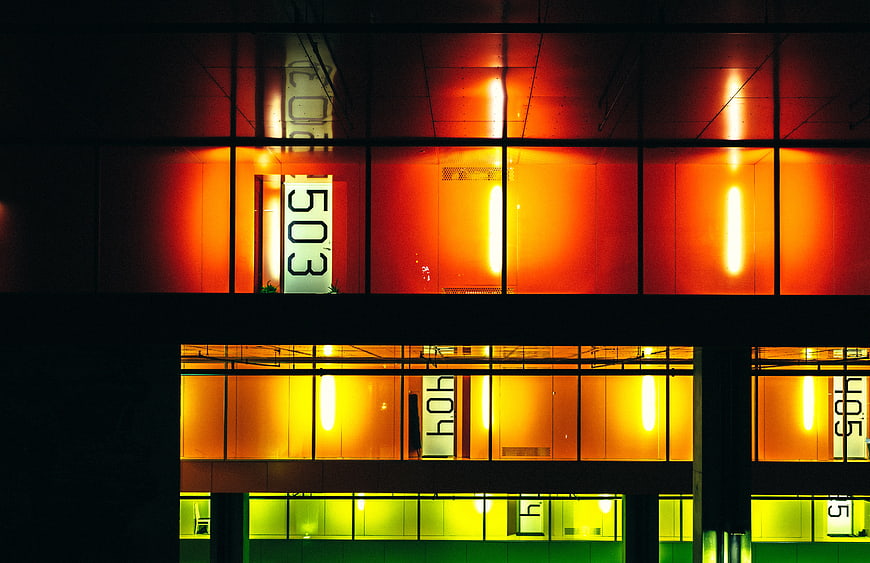 Abstract geometric building facade with glowing orange and yellow windows at night