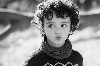 Black and white portrait of a child with curly hair looking sideways