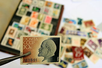 Soviet Lenin Postage Stamp Held By Tweezers Over Blurred Collection