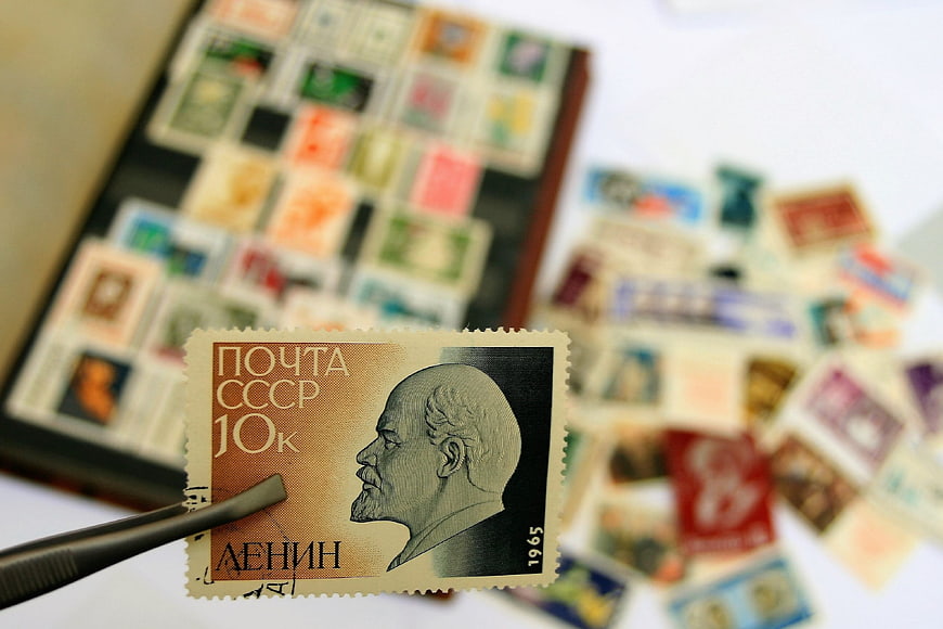 Soviet Lenin Postage Stamp Held By Tweezers Over Blurred Collection