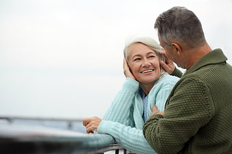 Happy Senior Couple Embracing on Balcony with Ocean View