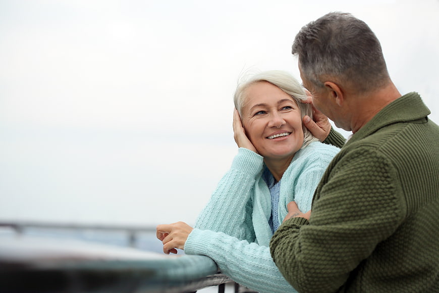 Happy Senior Couple Embracing on Balcony with Ocean View