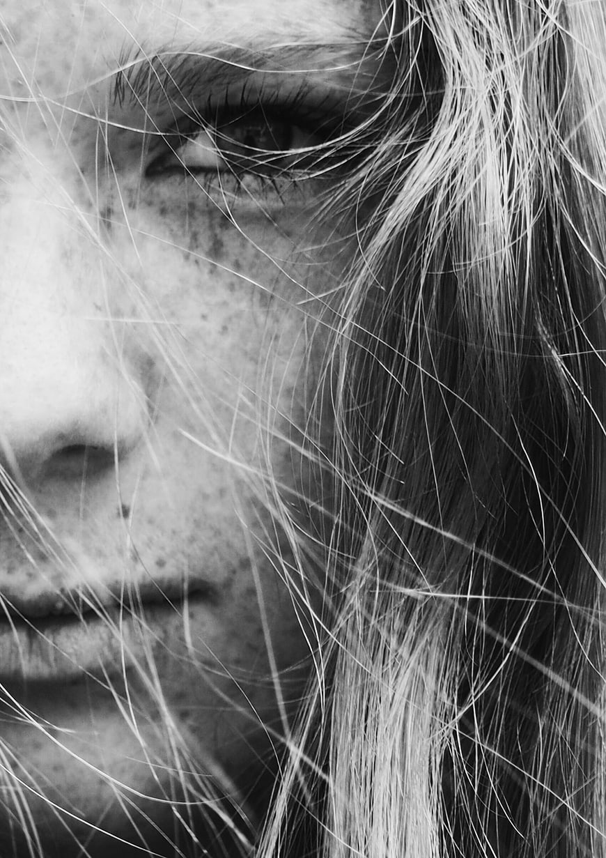 Close-up black and white portrait of woman with freckles and hair