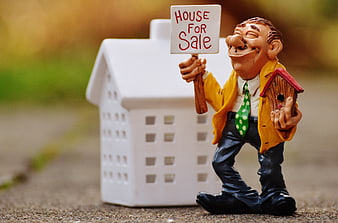 Real estate agent figurine holding house for sale sign