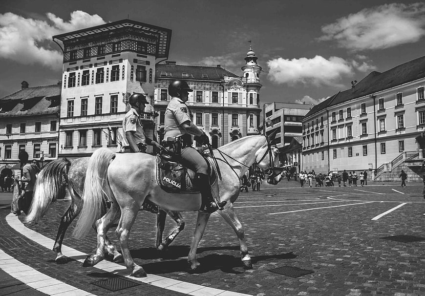Black and white photo of mounted police officers in a European town square
