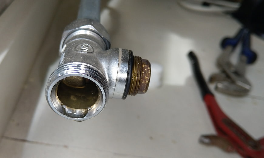 Close-up of metal plumbing valve with tools in background