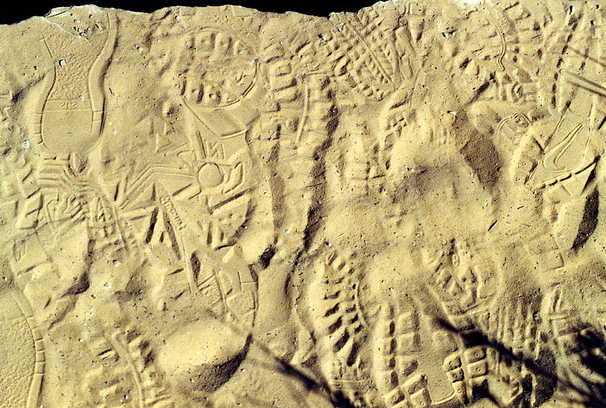 Close-up of textured sand with various shoe prints and patterns
