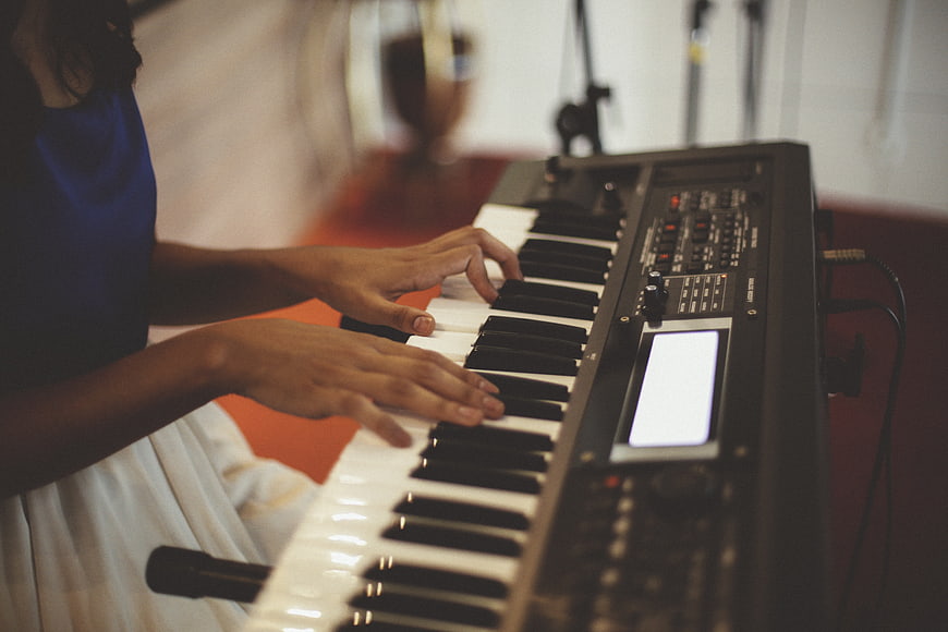 Close-up of hands playing electric keyboard in studio