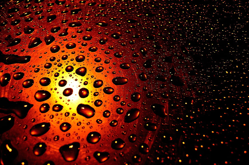 Macro water droplets on glass with warm sunset background