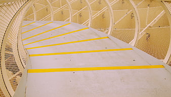 Curved concrete walkway with yellow safety stripes and metal mesh railing
