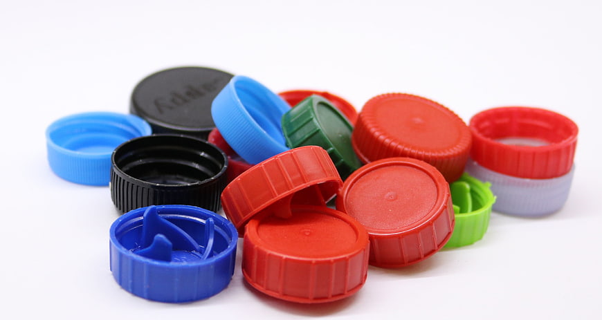 Colorful Plastic Bottle Caps Piled On White Background
