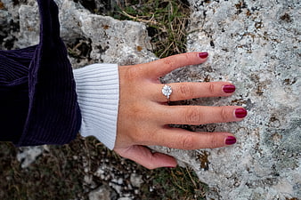 Woman's hand with diamond engagement ring on rock